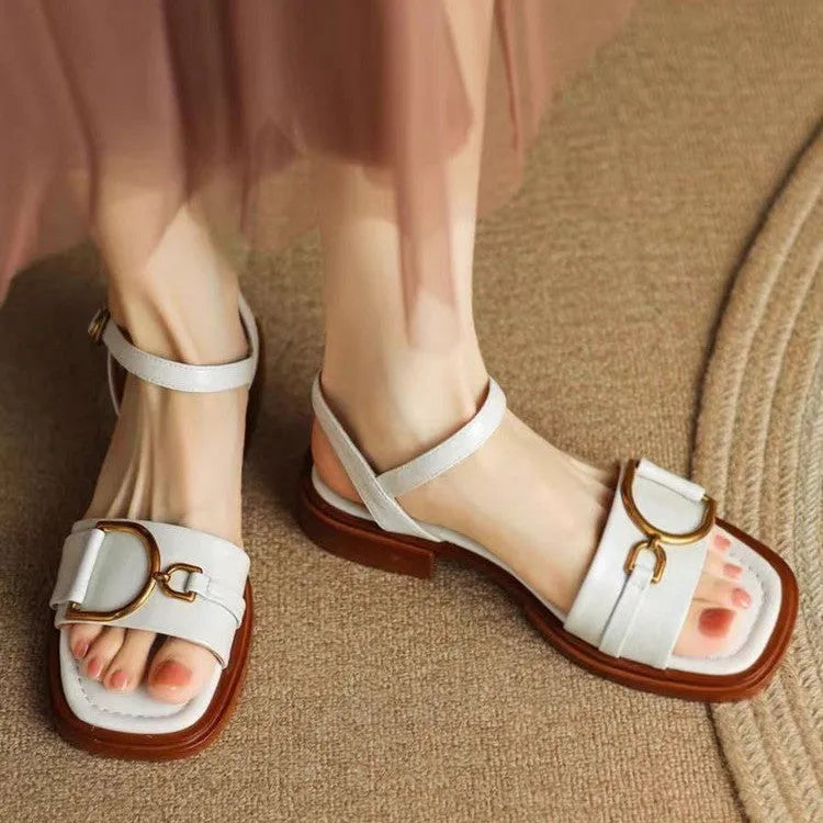 Women's black leather sandals with a thick rubber sole and button fastening on a round toe.