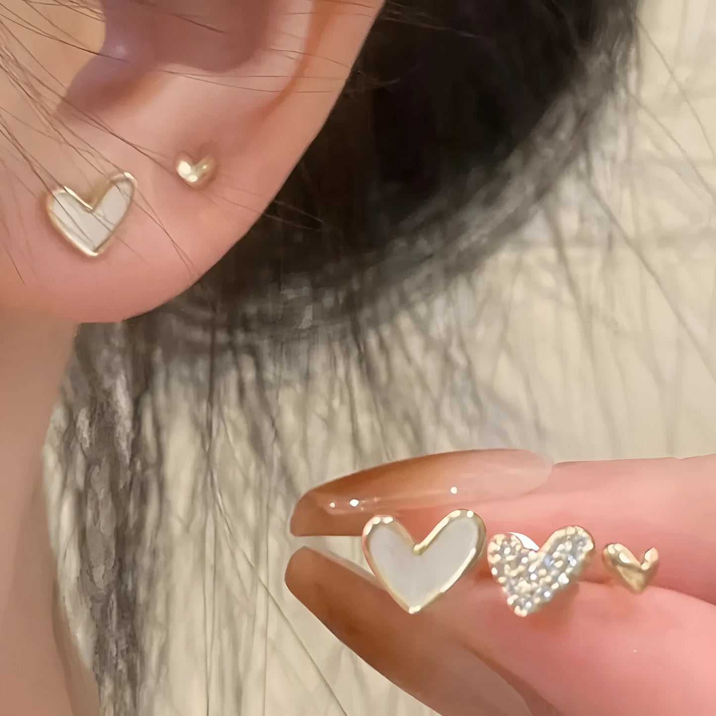 Three pairs of heart-shaped electroplated earrings in gold, black, black and white, and pink colours