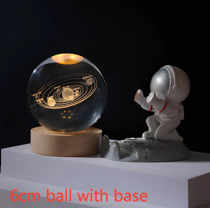 3D crystal ball night light projecting solar system pattern on wooden base with astronaut figurine