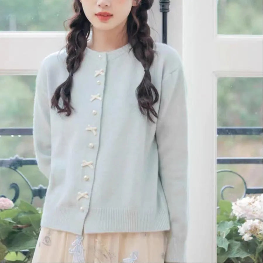 Women's solid colour cardigan sweater with bow pattern and pearl buttons in light blue.