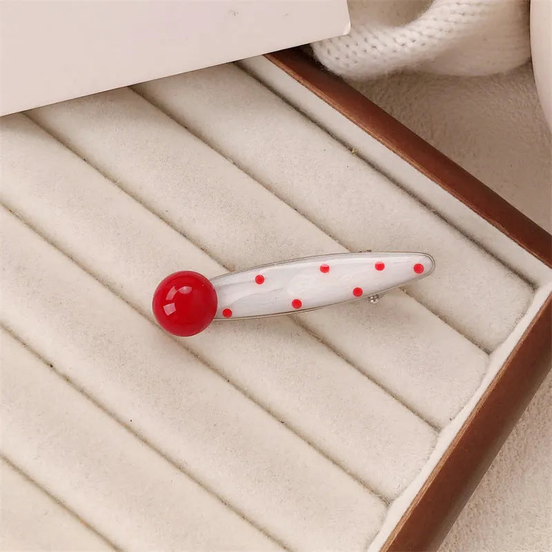 Red plastic hair clip with a 3D love heart and dots on a willow leaf-shaped base.
