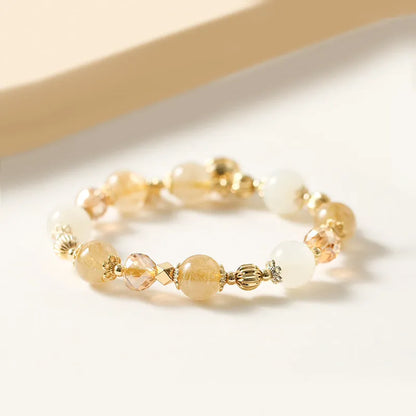 Gold-coloured rutilated quartz bracelet with a ringing bell charm on an adjustable band.