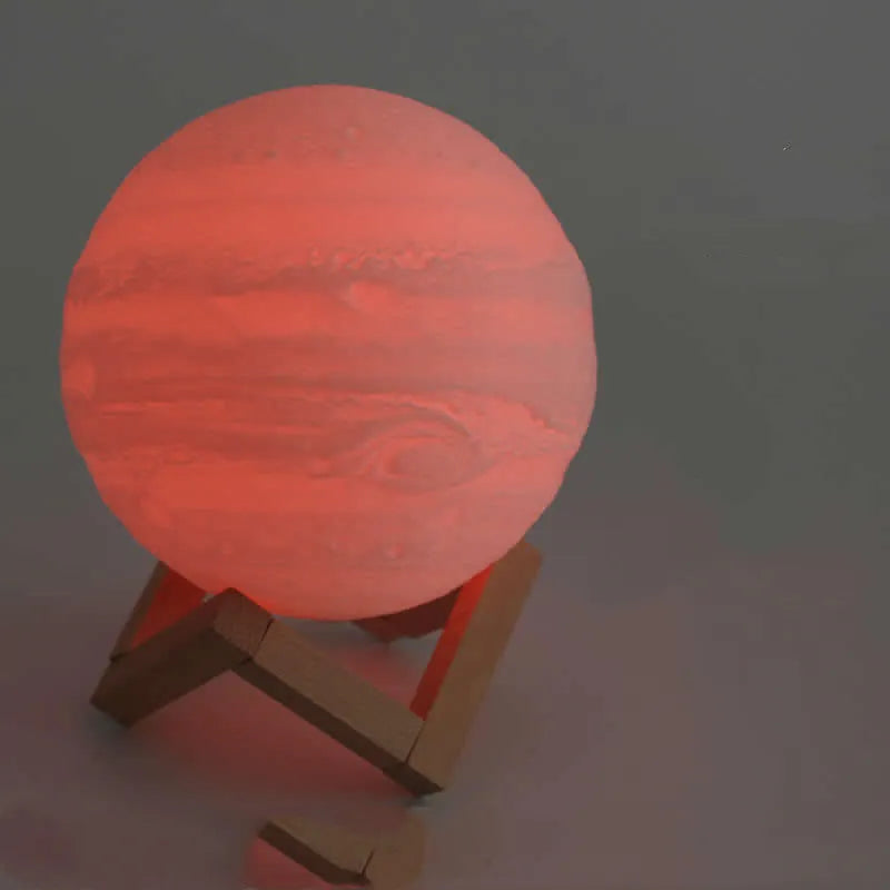 3D printed white moon lamp with detailed craters on a wooden stand, glowing with warm yellow light.