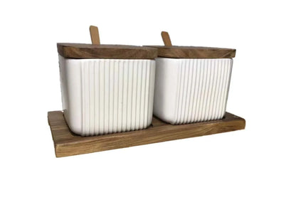 Elegant ceramic seasoning jars with wooden accents, providing stylish and organized storage for kitchen spices and herbs