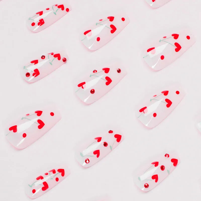 Sheet of 24 red diamond and cherry patterned nail art stickers with a small tube of adhesive glue.