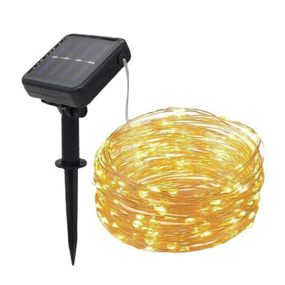 Solar-powered LED string lights arranged in garden with solar panel charging in sunlight