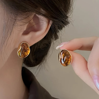 Three pairs of handmade alloy holiday earrings with geometric shapes and tassel details on display