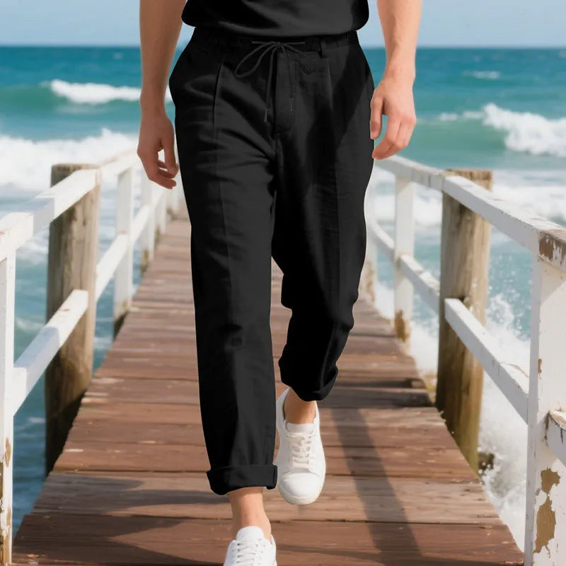 Men's light beige linen trousers with a loose straight leg and drawstring waist on a hanger.