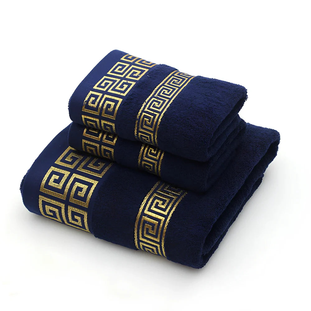 Three-piece cotton towel set showing 70cm bath towel and two 34cm hand towels in white, dark blue, and brown colours