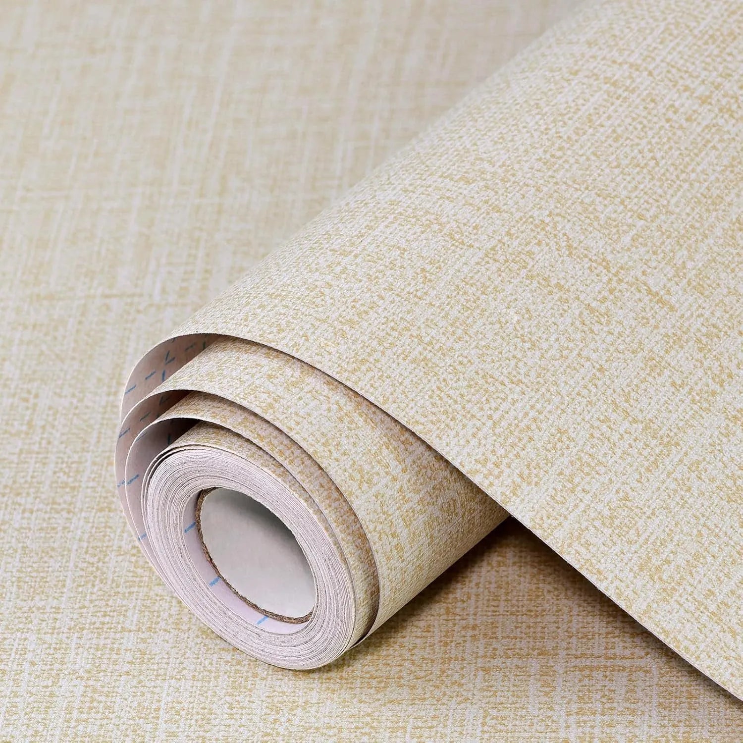 Roll of self-adhesive grey linen texture wallpaper next to a smooth application on a clean white wall.