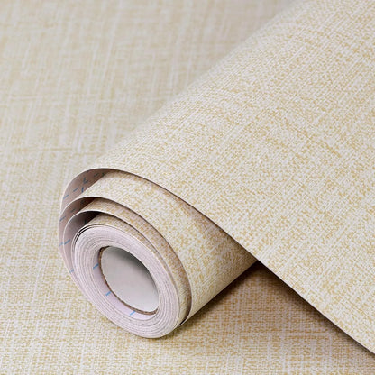 Roll of self-adhesive grey linen texture wallpaper next to a smooth application on a clean white wall.