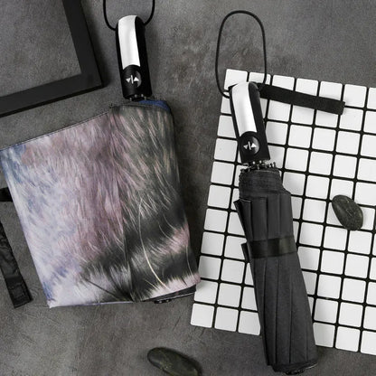 Folding umbrella showing tri-fold design with gesture motif and plastic handle