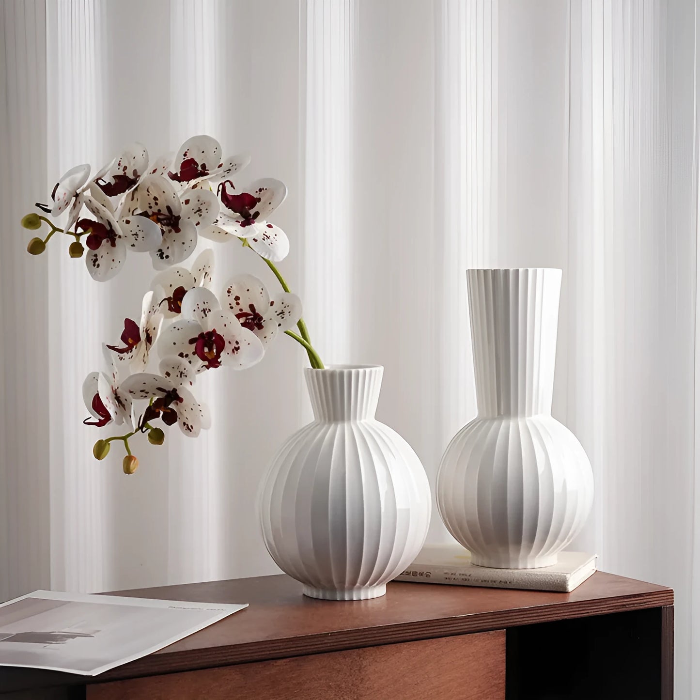 White ceramic ball-shaped vase with striped pattern, shown in small and large sizes with orchid arrangements
