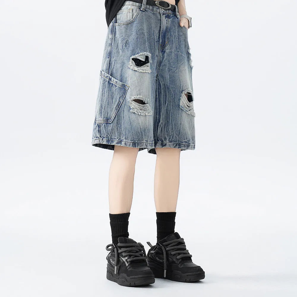 Man wearing loose fit black ripped denim shorts with distressed detailing and a washed vintage finish.