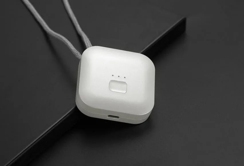 Pink wearable USB air purifier necklace on a table with USB cable, showing compact size.
