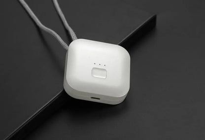 Pink wearable USB air purifier necklace on a table with USB cable, showing compact size.