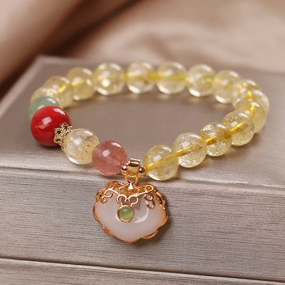Women's yellow citrine jade ruyi pendant bracelet on wrist, alloy construction.