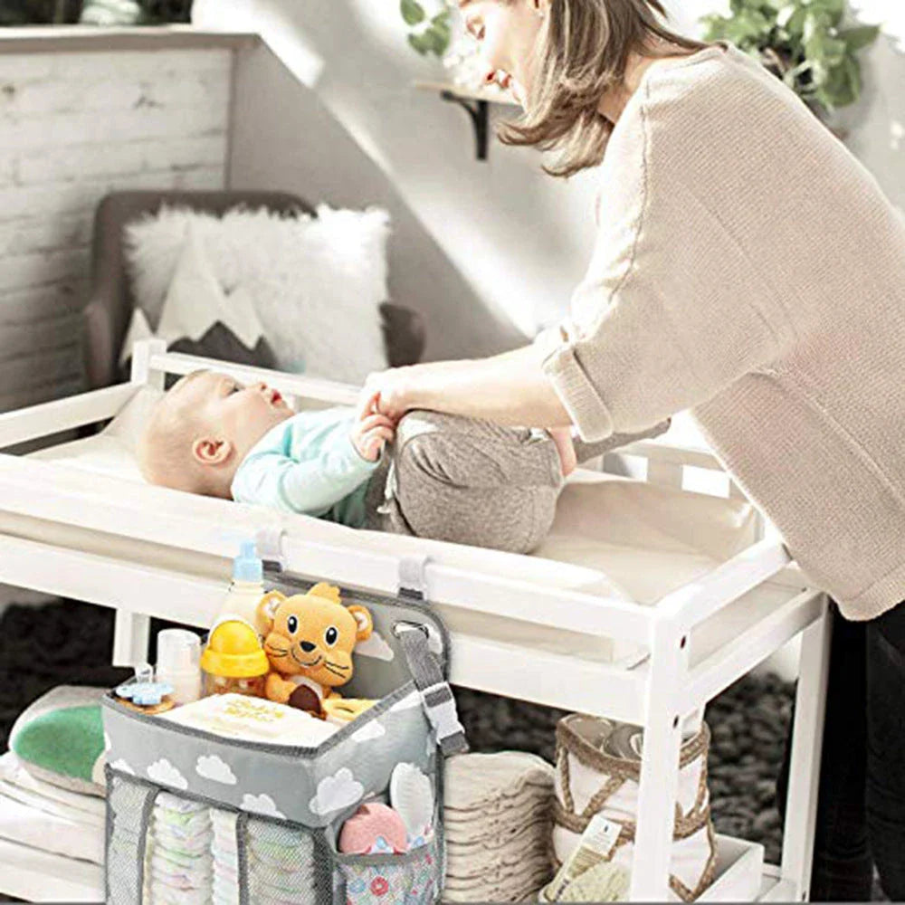 Portable baby crib organizer with hanging storage pockets for diapers, bottles, toys, and other nursery essentials