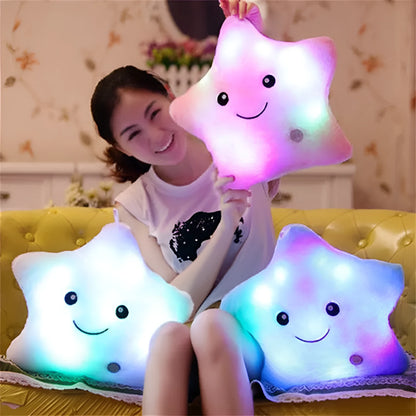Colourful glowing five-pointed star plush pillow on a dark background.