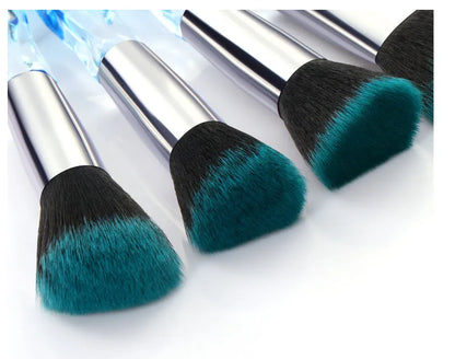 Ten clear crystal-handled foundation brushes with black synthetic bristles laid out on a surface.