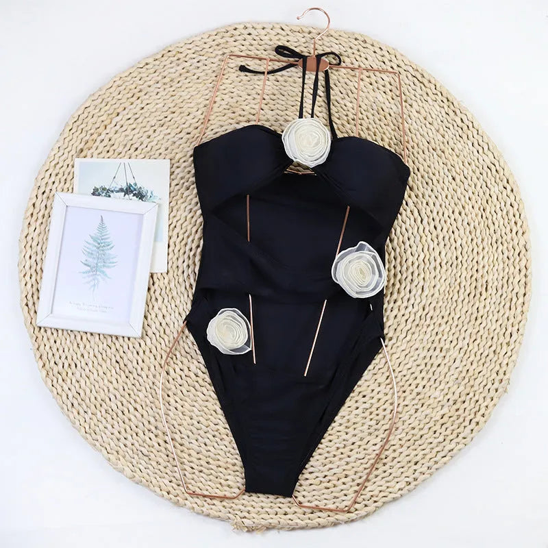 Women's black one-piece swimsuit with 3D flower print and bikini-style design for swimming and sports.