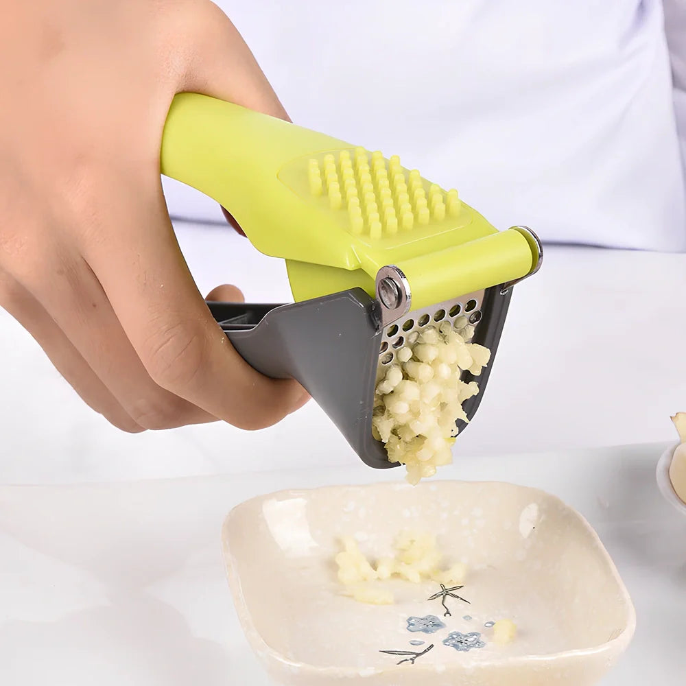 White plastic garlic masher with stainless steel crushing grid and ergonomic handle for kitchen use