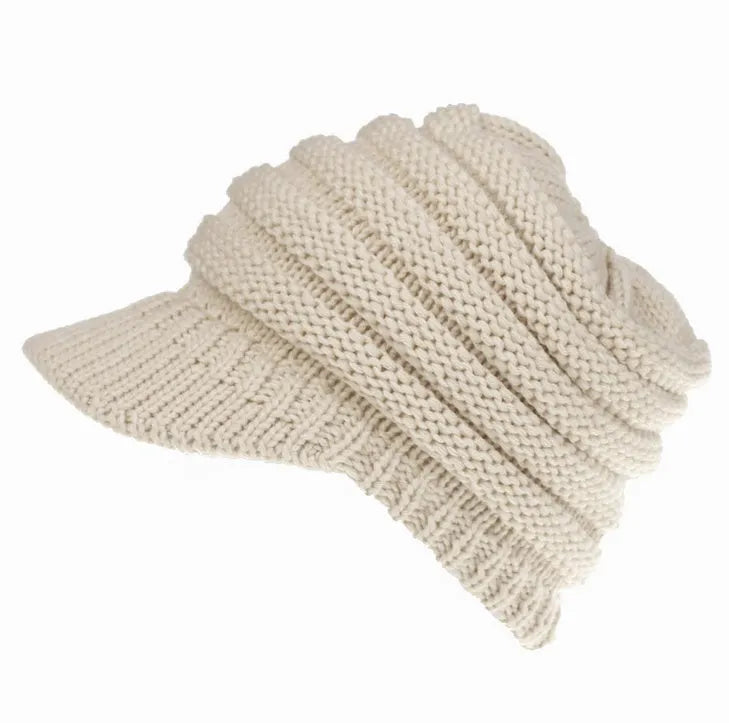 Woman wearing a light grey knitted ponytail beanie with her ponytail pulled through the hole in the back.