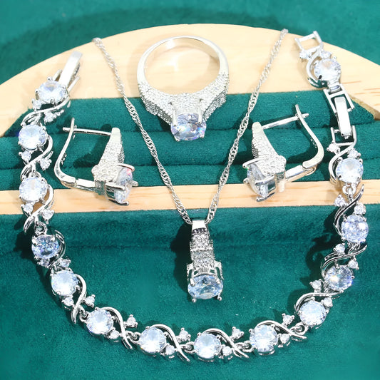 Four-piece bridal jewellery set with zircon pendants on a water wave chain, showing necklace, bracelet, earrings and ring.