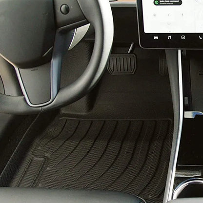 Black TPE rubber floor mats for Tesla Model 3, showing deep grooves and raised edges on driver's side.