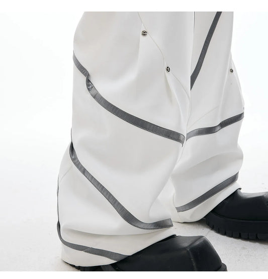 Men's trousers with three-dimensional cutting and metal striped rivet pleats in black or white, showing tailored fit and detail