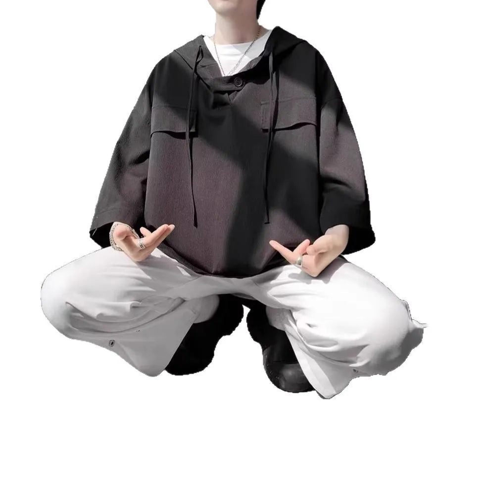 A man wearing a loose-fit black hooded short sleeve t-shirt for summer.