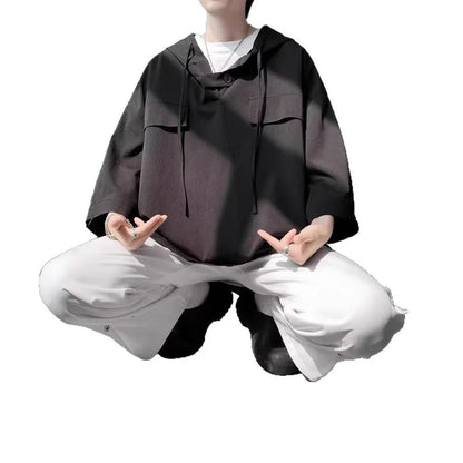 A man wearing a loose-fit black hooded short sleeve t-shirt for summer.