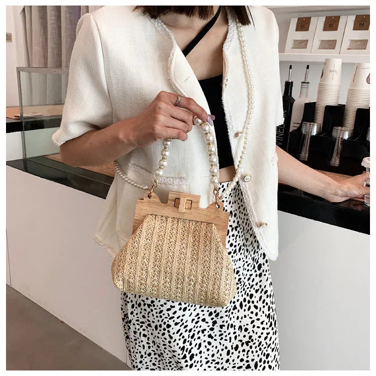 Women's beige straw woven shoulder bag with pearl chain strap, showing horizontal square shape and sewing line detail.