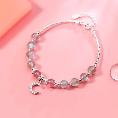 Natural moonlight-coloured moonstone bracelet with silver crescent moon charm on adjustable chain.