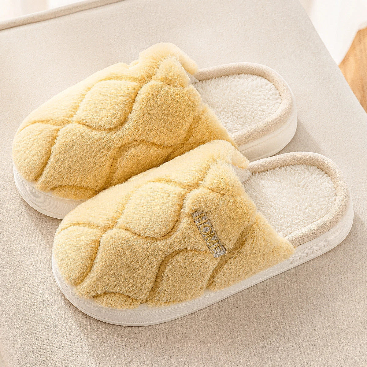 Cozy plush slippers in various colors, including light gray, khaki, yellow, and pink, with a soft plush upper and durable PVC sole for indoor and outdoor use.
