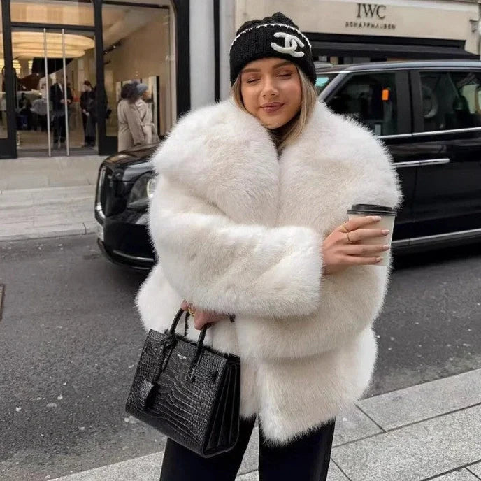 Women's white artificial fur coat with large lapel, long sleeves, and deep pockets shown in street fashion setting