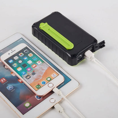 Orange and green hand solar power bank with solar panel, USB ports, and LED light showing 12000mAh capacity