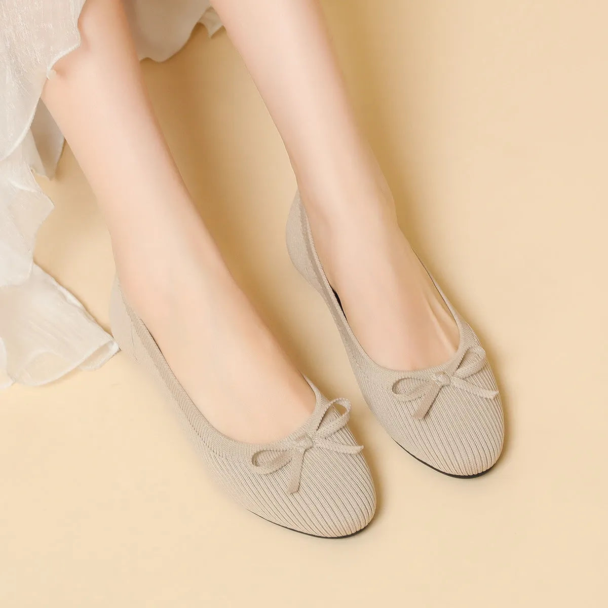 Women's black fabric flat pumps with a bow detail on the round toe, shown on a white background.