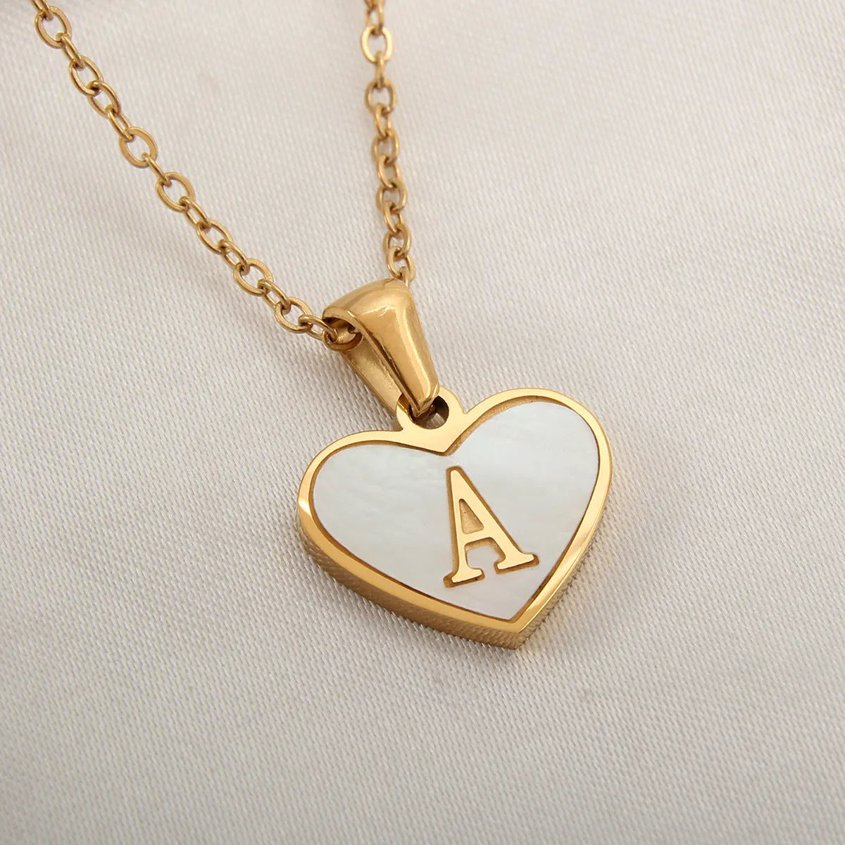 Gold-plated clavicle necklace with a white shell heart pendant, personalised with a letter from A to Z.
