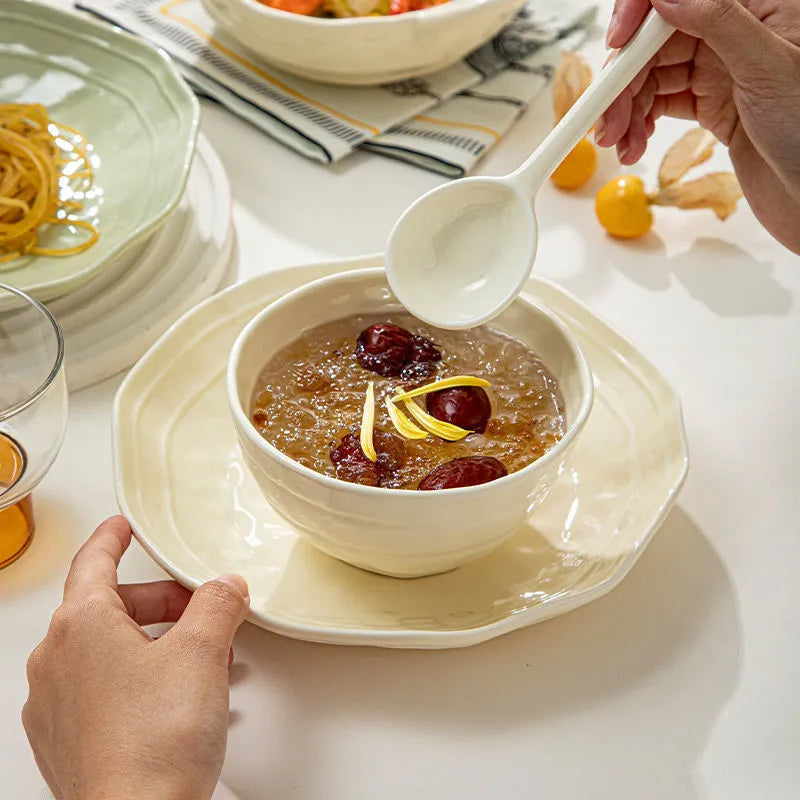 Boxed set of seven solid-colour ceramic plates and bowls on a table.