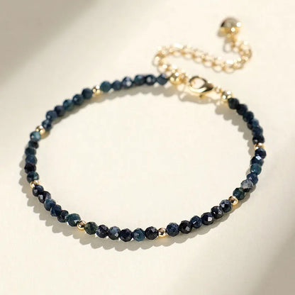 Close-up of a blue tourmaline beaded bracelet with 3mm stones and spacer beads on a wrist.