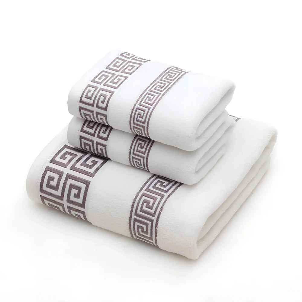 Three-piece cotton towel set showing 70cm bath towel and two 34cm hand towels in white, dark blue, and brown colours