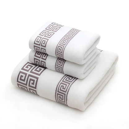 Three-piece cotton towel set showing 70cm bath towel and two 34cm hand towels in white, dark blue, and brown colours