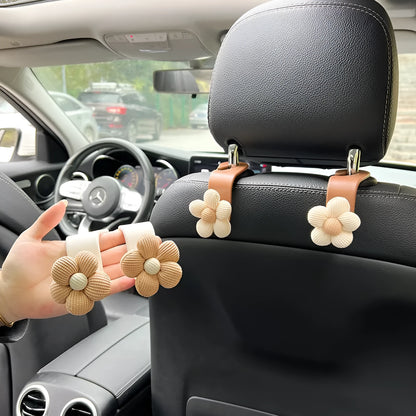 Khaki coloured plastic car seat hook with floral pattern for storage, shown at 11 by 5.5 cm.