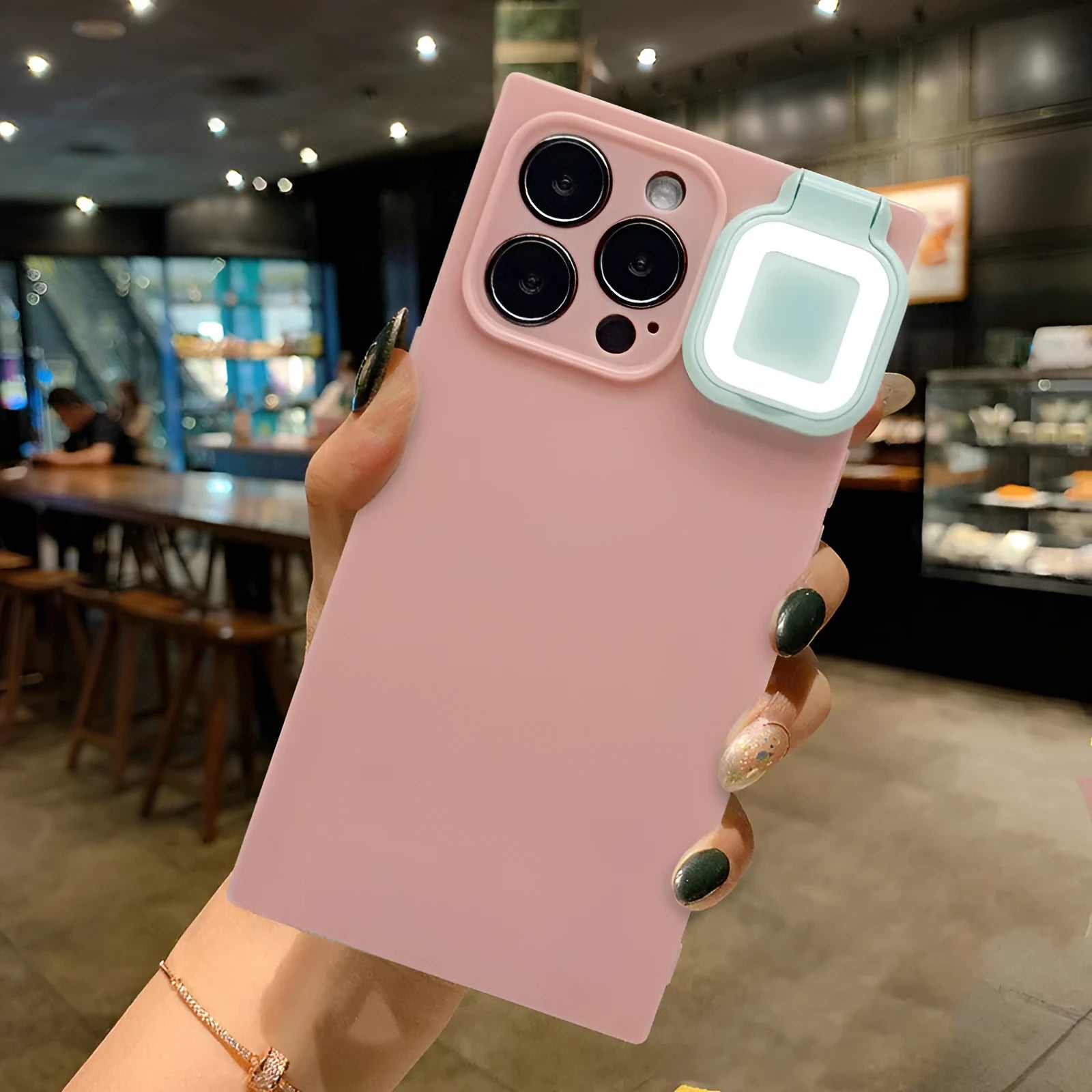 Pink mobile phone case with built-in ring flash light for Apple iPhone 13 models on a white background.