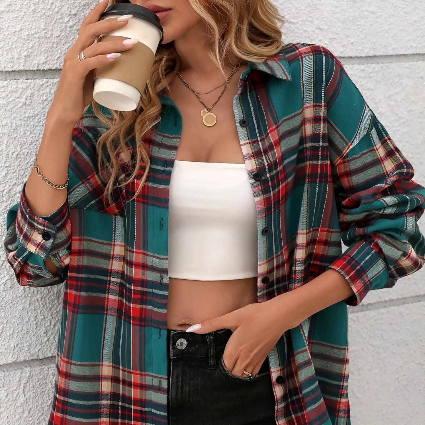 A woman modelling a loose-fit black, green, and purple plaid shirt with long sleeves.