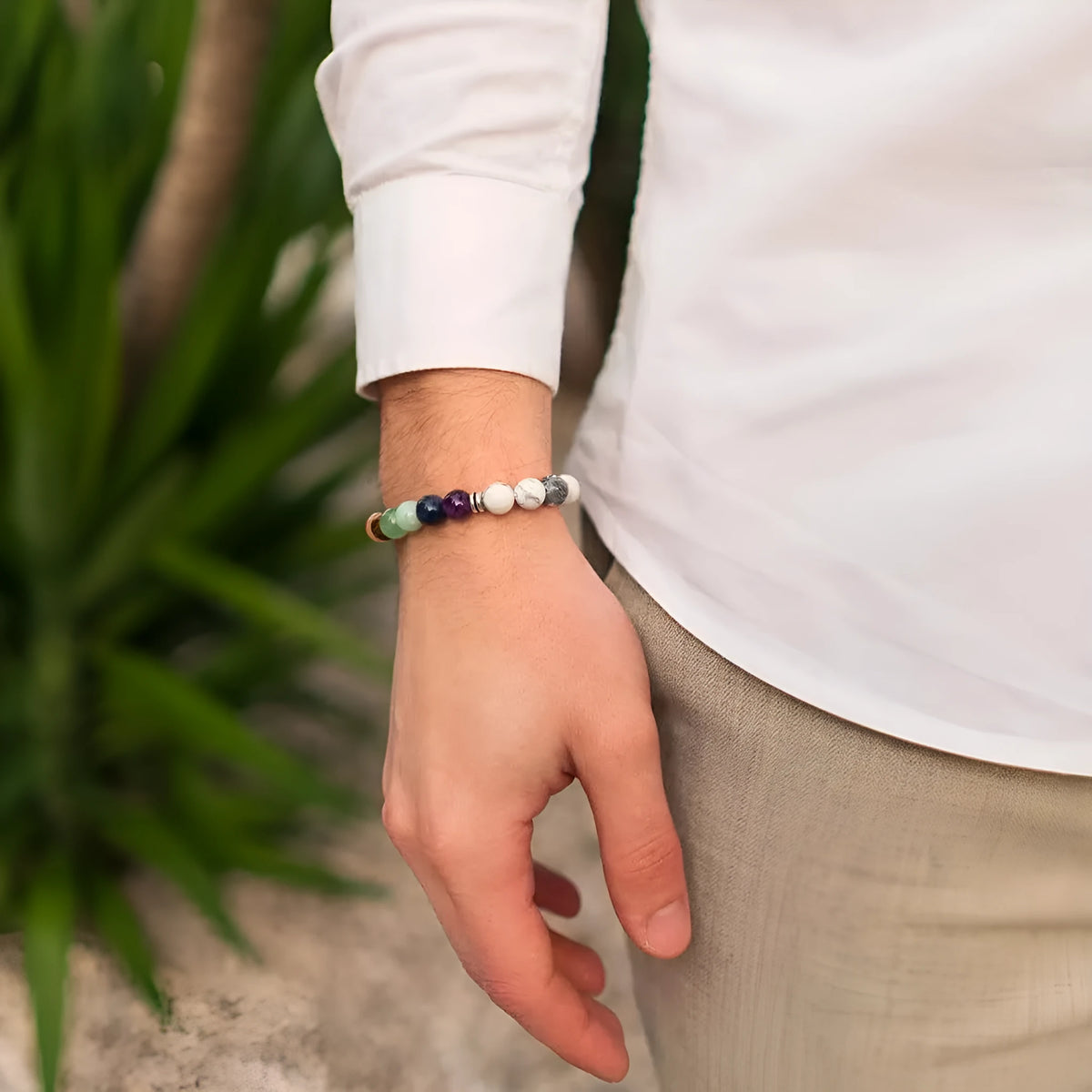 Close-up of a women's flat knot braided healing bracelet hand-woven with colourful gemstones.
