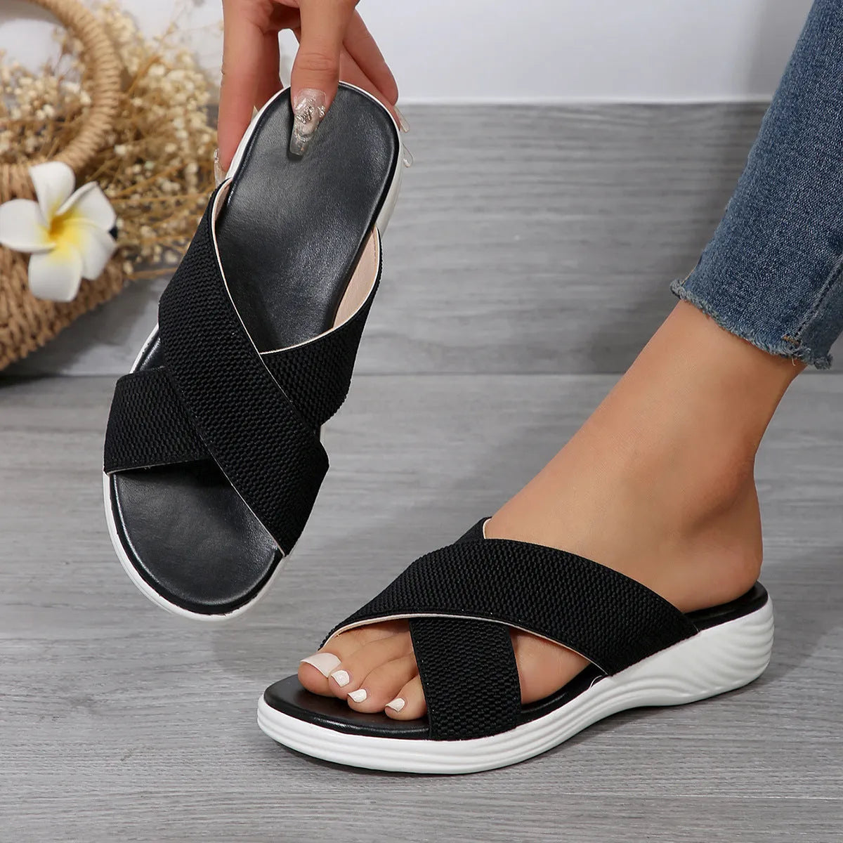 Women's black wedge-heel slippers with peep toe and cross-strap design on a thick rubber sole.