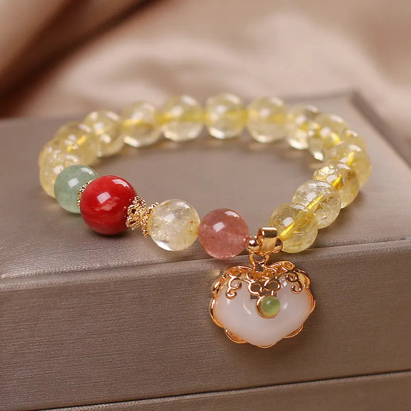 Women's yellow citrine jade ruyi pendant bracelet on wrist, alloy construction.