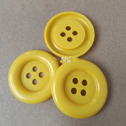 Assorted oversized round plastic buttons in various colours showing four-hole sew-through design.